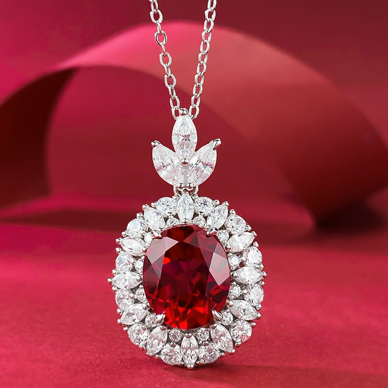 Aeterna Jewelry oval ruby pendant necklace with diamond halo on red backdrop
