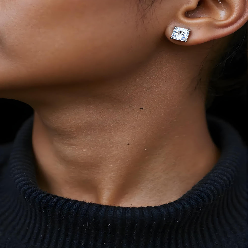 Model with dark skin wearing Asscher cut diamond stud earrings by Aeterna Jewelry, timeless luxury minimalist look with refined sparkle