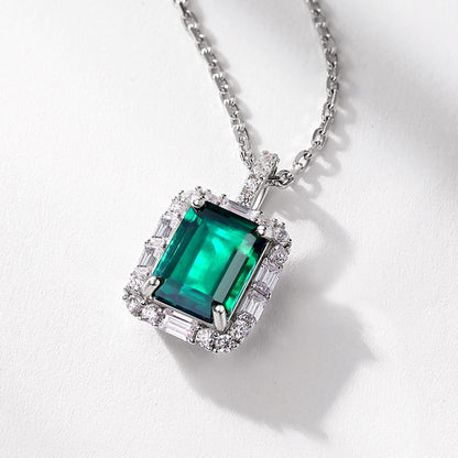 Aeterna Jewelry emerald pendant close-up on white surface, elegant lighting