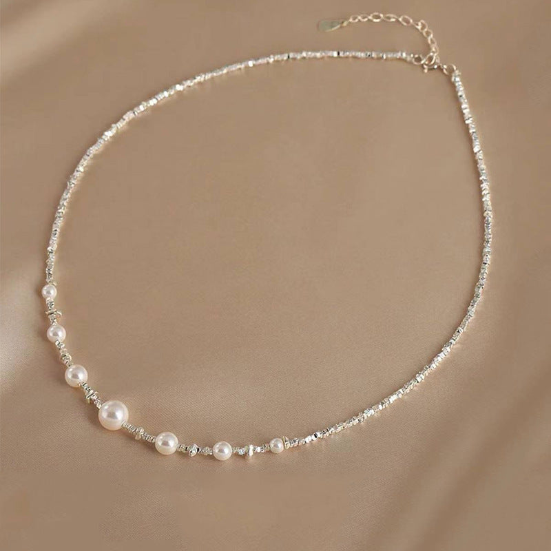 Asymmetric freshwater pearl and silver textured chain necklace by Aeterna Jewelry, minimalist design photographed on soft beige background.
