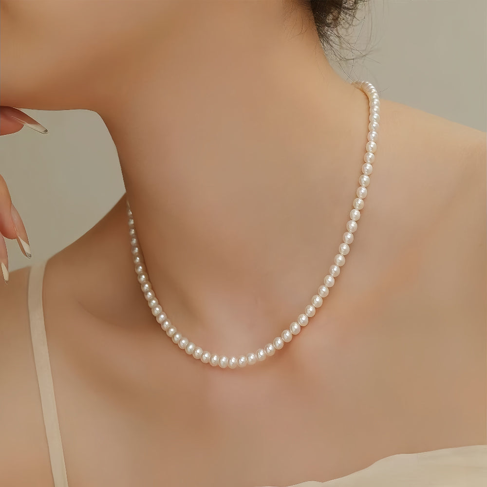 Close-up of woman wearing Aeterna Jewelry freshwater pearl necklace, elegant neckline portrait highlighting timeless natural luster